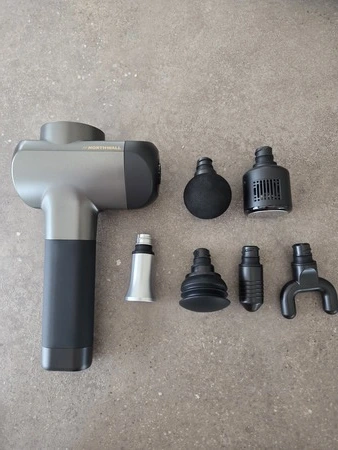 Northwall G1 massage gun met opzetstukken op tafel, getest door fysioengezond.nl