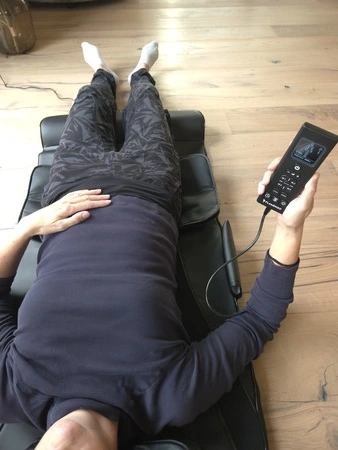 Flamengo InfraStretch massagemat in ruglig op de mat met afstandsbediening in hand, getest door fysioengezond.nl